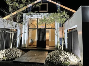 A modern hotel entrance with a glass door, a small garden area with rocks, and a pathway leading to the door. - HOTEL Fuuga Luxury Resort - Adults Only (Maizuru)