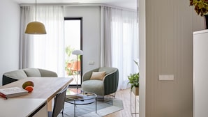 A modern living room with a dining table, two chairs, a round coffee table, and a pendant light. - 60 Balconies Iconic (Madrid)
