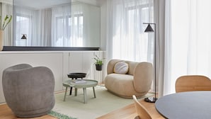 A modern living room with a grey armchair, a beige sofa, a small round table, and a floor lamp. - 60 Balconies Iconic (Madrid)
