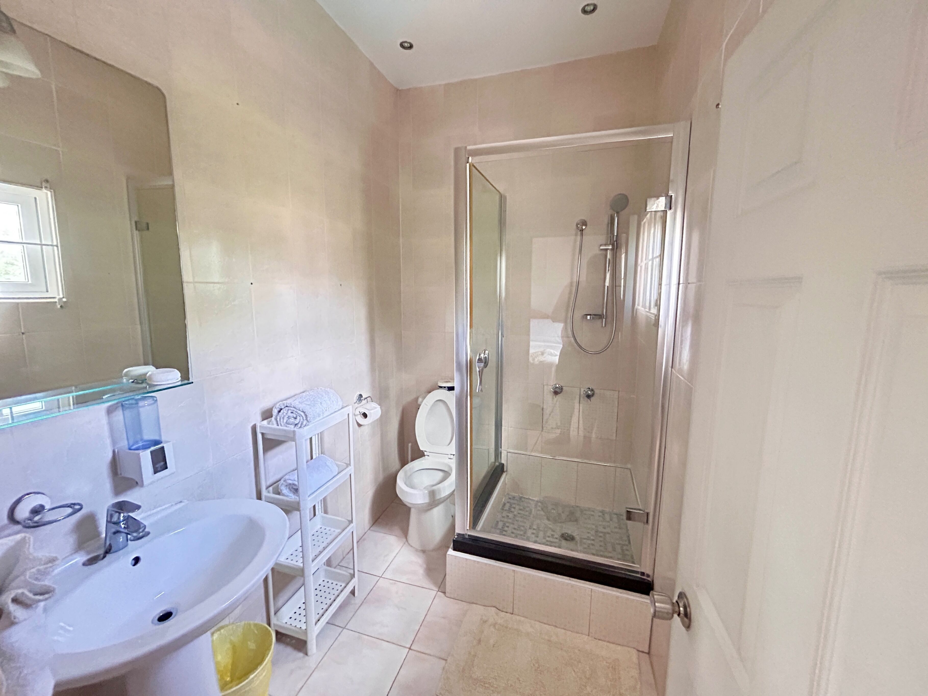 Een moderne badkamer met een douchecabine van glas, een wit wastafelmeubel en een toilet.