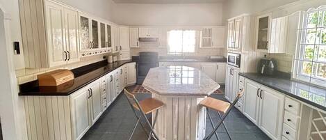 A spacious kitchen with white cabinetry, a central island, and a ceiling fan.