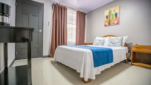A neatly arranged bedroom with a bed, a bedside table, a desk, and a painting on the wall. - Hotel La Vid (La Fortuna)