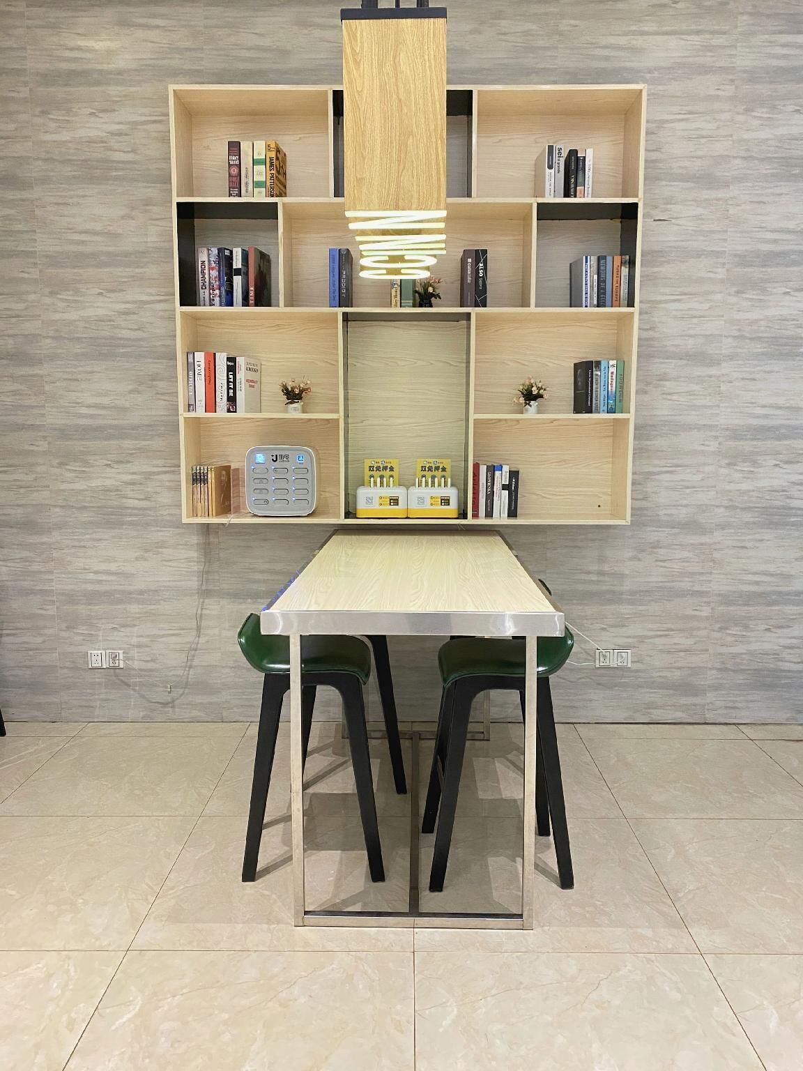 A modern room with a wooden bookshelf, a table with chairs, and a wall-mounted light fixture.