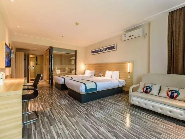 Una habitación de hotel con una cama grande, un escritorio, una silla, un sofá y un espejo.