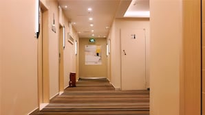 Un couloir d’hôtel avec des revêtements de sol en moquette, des portes des deux côtés et un panneau indicateur au bout.