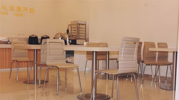 Un comedor moderno con varias mesas y sillas, una barra con caja registradora y una pared con texto.