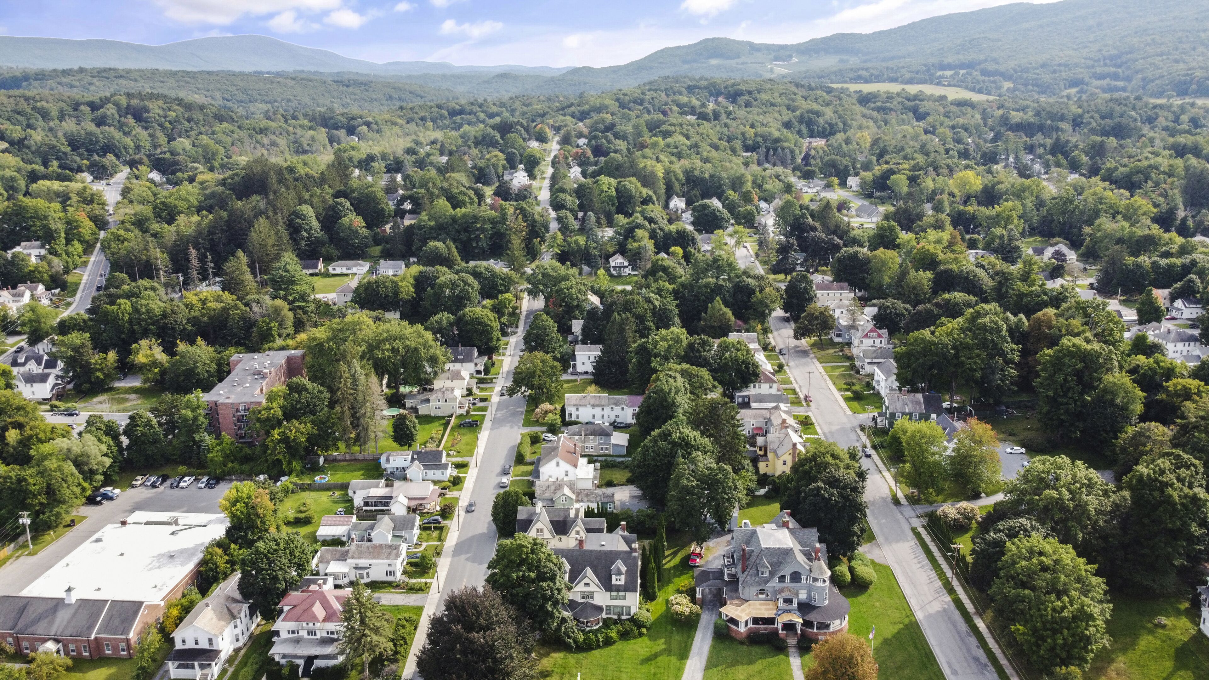 An aerial view of a residential area with houses, roads, and surrounding greenery.