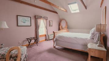 A bedroom with a bed, a chair, a desk, a mirror, and a window.