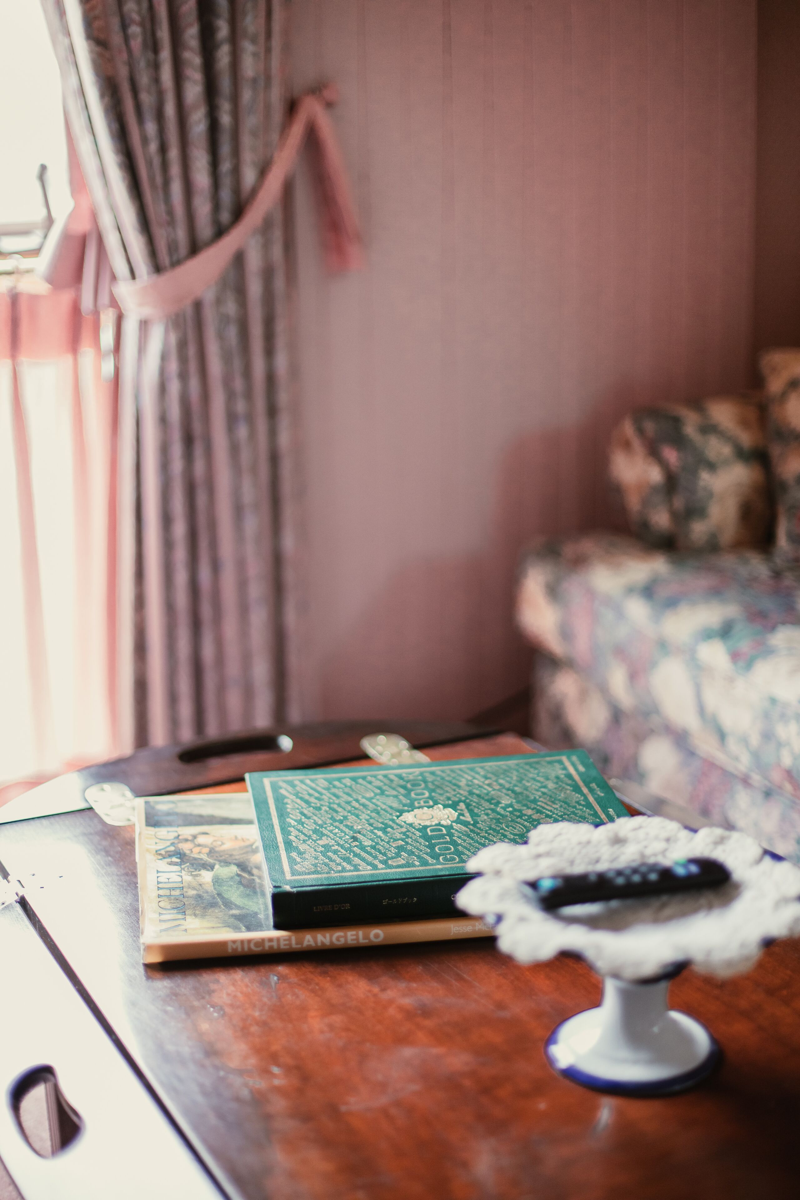 A wooden table with a book, a remote control, and a decorative item.
