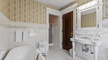 A bathroom with a freestanding bathtub, a vanity with a mirror and lights, and a shower area.