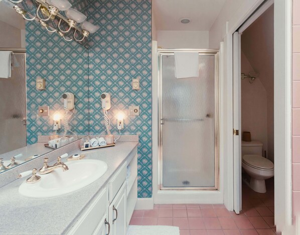 Une salle de bain avec un grand miroir, deux lavabos, une douche et des toilettes.