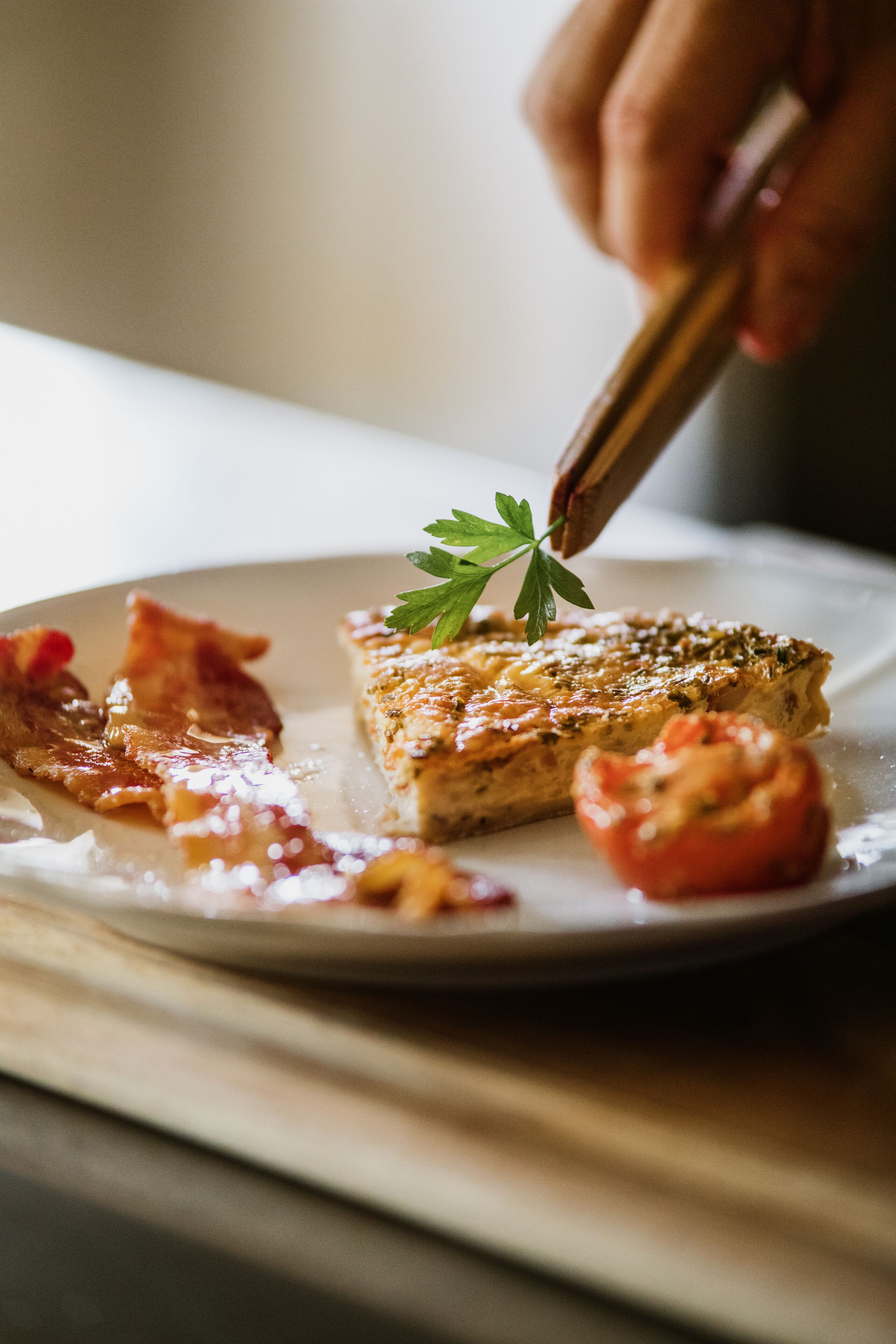 A close-up of a breakfast plate with a piece of toast, bacon, and a tomato.