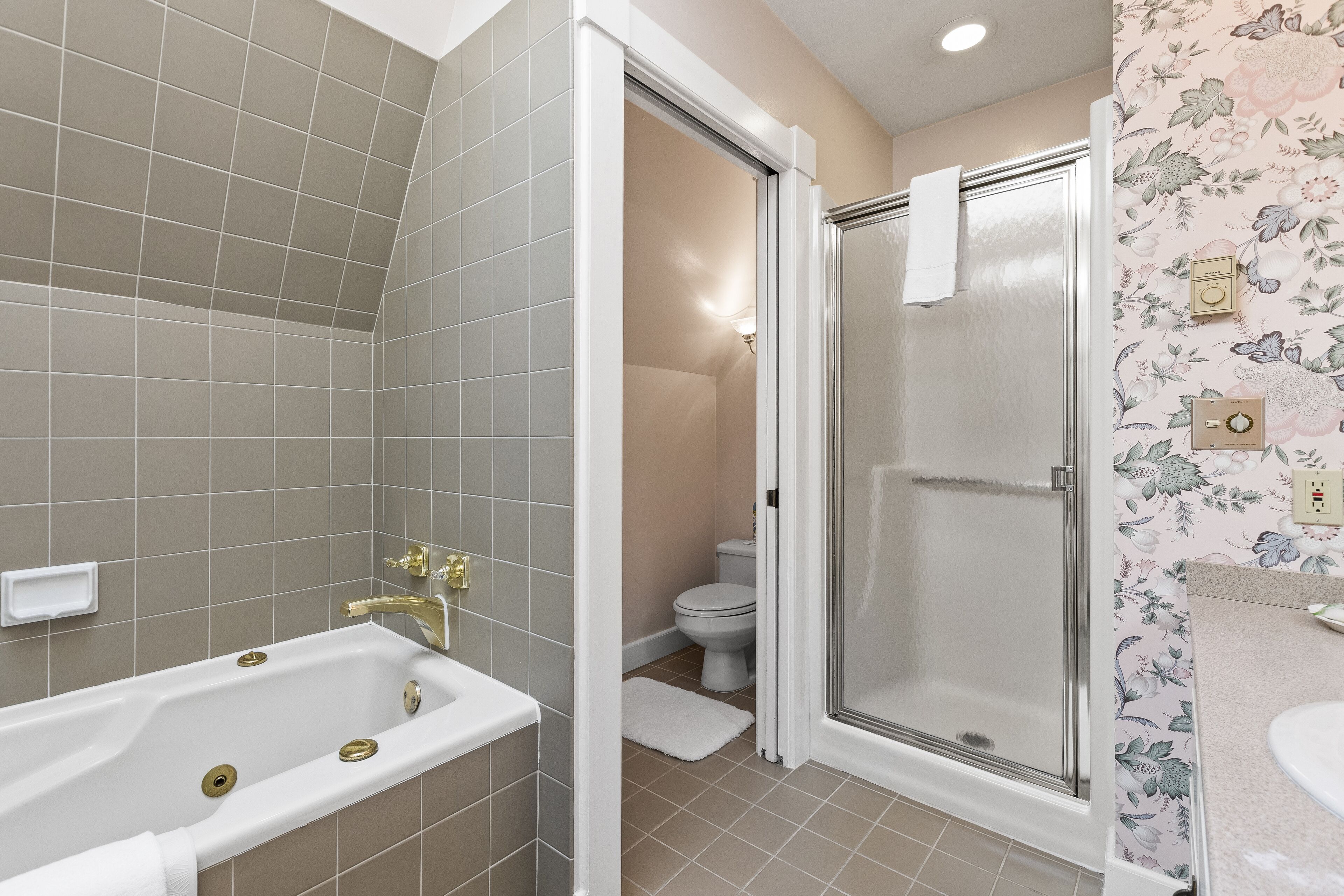 A bathroom with a bathtub, toilet, and shower area.