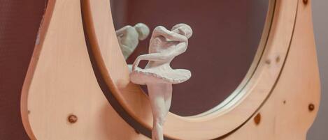 A wooden dresser with a mirror, a ballet dancer figurine, and a book.