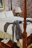 A neatly made bed with a wooden headboard, a bedside lamp, and a framed picture on the wall.