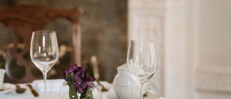 A dining table set with white tablecloth, gold cutlery, and a white cup and saucer.