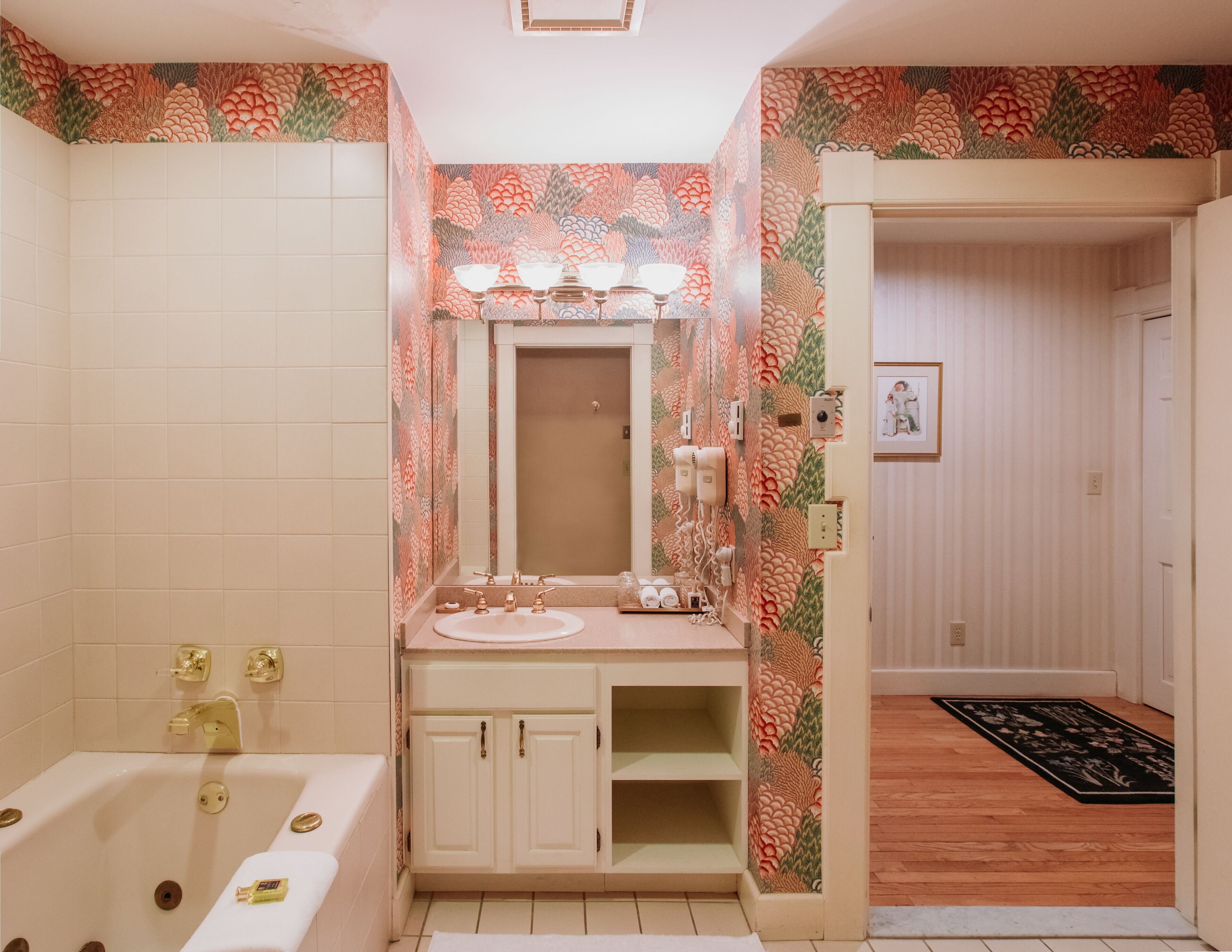 A bathroom with a sink, vanity, and bathtub.