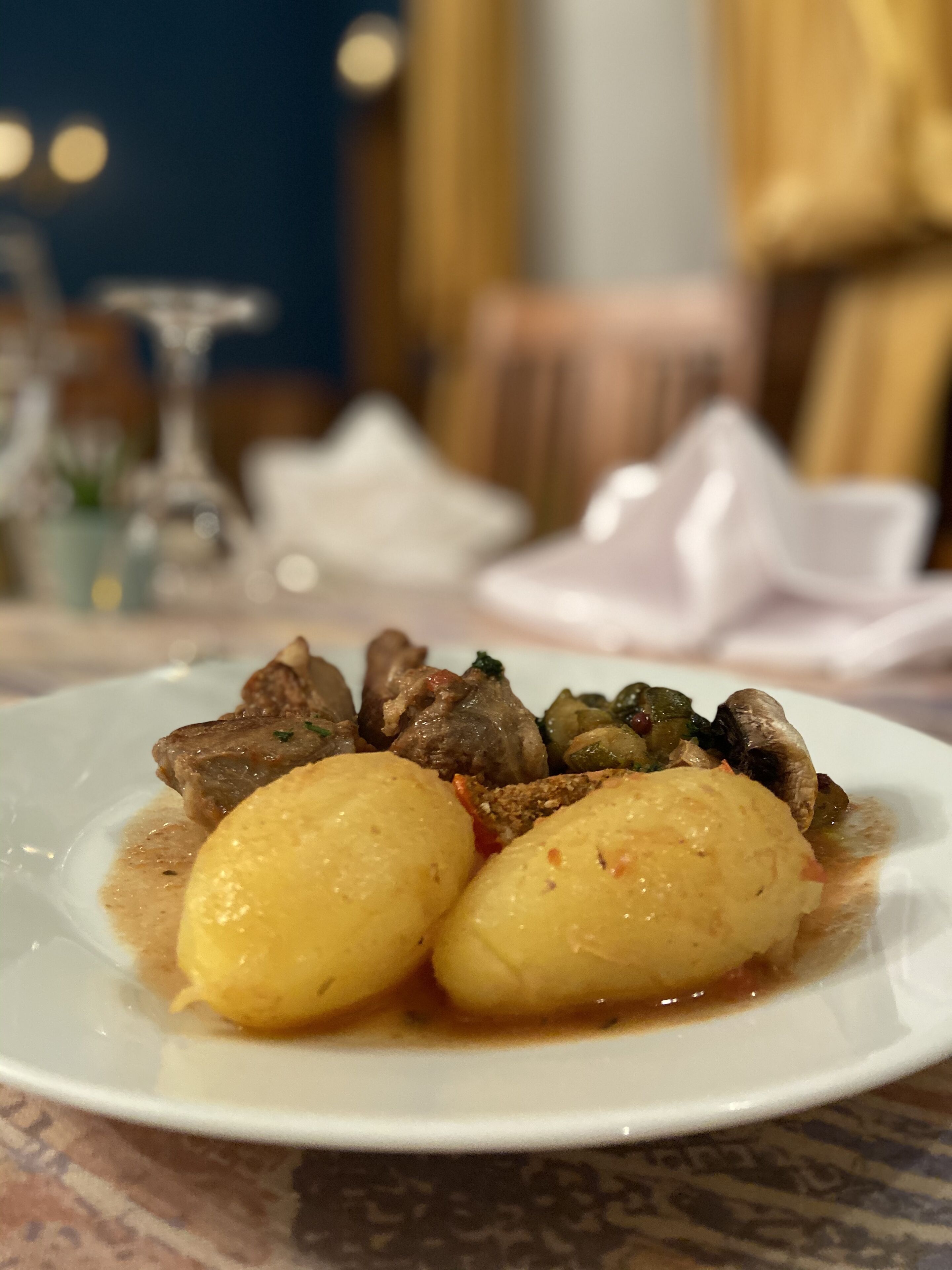 Een bord eten met vlees en aardappelen, geserveerd op een wit bord.