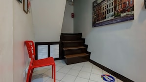 Una escalera con una silla roja y un cuadro enmarcado en la pared.