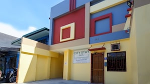 Un edificio con el rótulo de City Stay Inns, que presenta un diseño moderno con formas geométricas y una combinación de colores amarillo, azul y rojo.