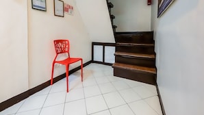 Una escalera con una silla roja y diplomas enmarcados en la pared.