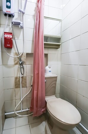 Un baño pequeño con inodoro, ducha y dispensador de jabón.