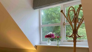 Una habitación acogedora con ventana, una lámpara, una mesita con un florero y una lámpara de pie alta.