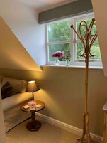 Una habitación acogedora con ventana, una lámpara, una mesita con un florero y una lámpara de pie alta.