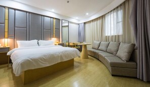 A modern hotel room with a large bed, a sofa, a small round table, and a mirror. - Ji Hotel (Wuhan)