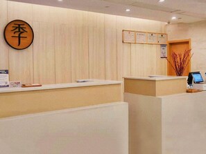 A reception desk area with a wooden sign, framed certificates, and a computer monitor. - Ji Hotel (Wuhan)