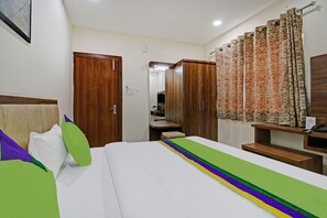 A hotel room with a bed, wooden wardrobe, a desk, and a mirror. - Treebo Krishna Regency ISBT Bus Stop (Bhopal)
