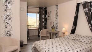 Une chambre d’hôtel avec un lit, une chaise, une table avec une lampe et une vue sur l’extérieur.