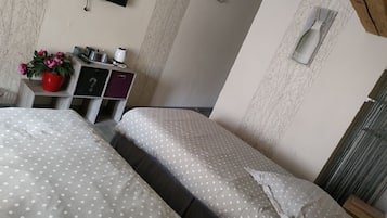 A hotel room with two beds, a desk with a computer, a TV, and a window with curtains.