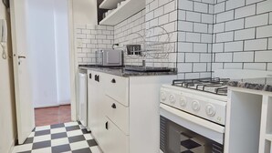 A kitchen with white cabinets, a microwave, a gas stove, and a checkered floor. - Hestia at Arenales 1200 (Buenos Aires)