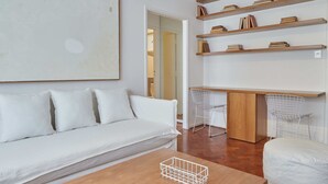 A modern living room with a white sofa, wooden coffee table, and a bookshelf with books. - Hestia at Arenales 1200 (Buenos Aires)