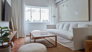 A modern living room with a white sofa, a wooden coffee table, and a TV on the left. - Hestia at Arenales 1200 (Buenos Aires)