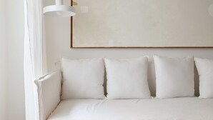 A white sofa with four cushions, a white wall, and a white floor lamp. - Hestia at Arenales 1200 (Buenos Aires)