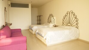 Quarto com duas camas, uma cadeira rosa e uma pequena mesa.