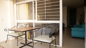 Uma sala de estar com área de refeições, mesa e duas cadeiras, sofá com almofadas listradas e um sofá verde-água.