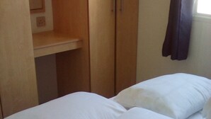 Un dormitorio con cama, armario y ventana con cortinas.