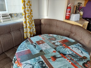A corner sofa with a patchwork tablecloth, a fire extinguisher, and a toaster on a counter. - Arizona Family and Dogs Welcome Caravan 3 Bedrooms (Rye)