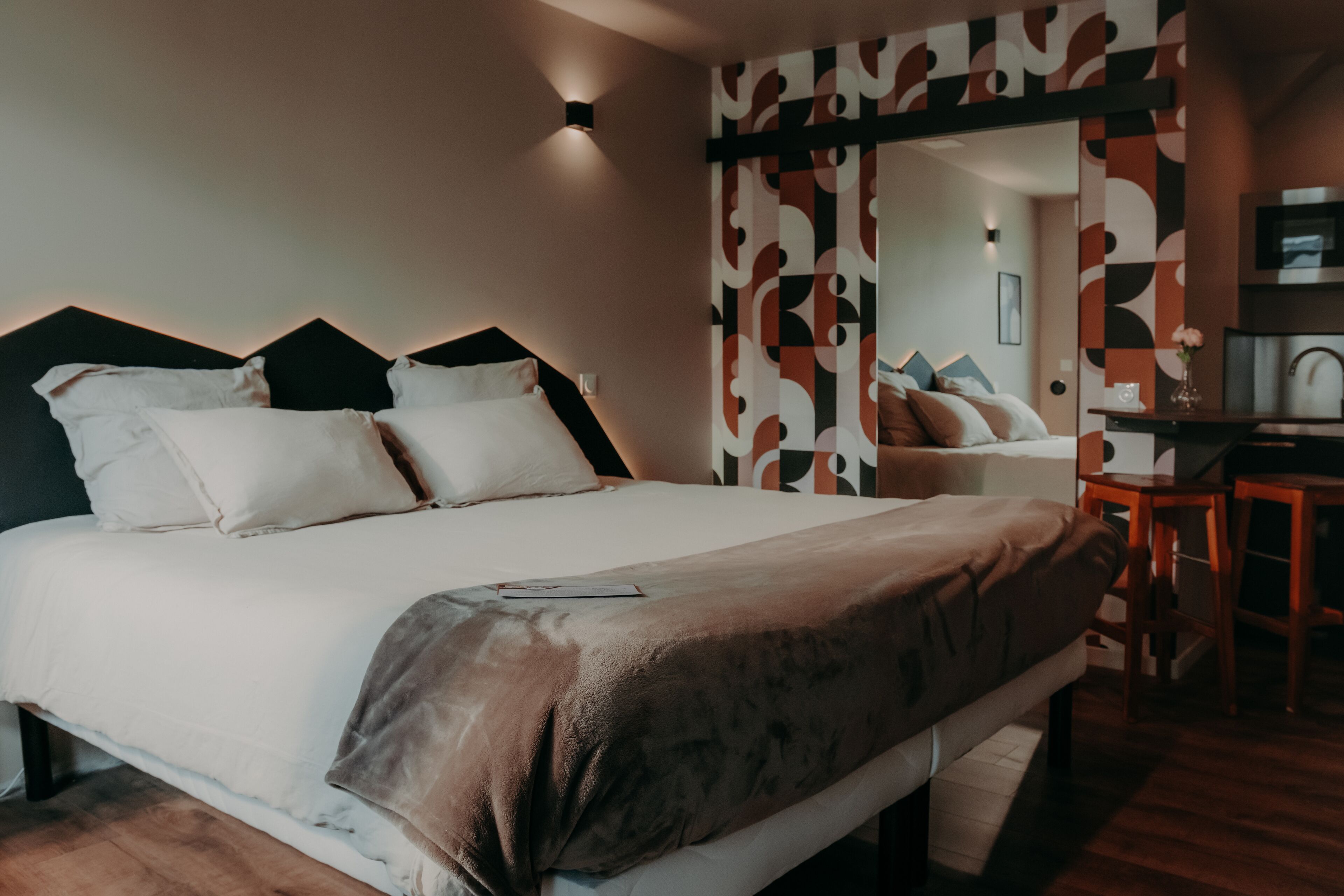 Una habitación de hotel moderna con una cama grande, un escritorio y un espejo.