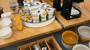 A breakfast buffet setup with various food items, utensils, and condiments. - Le Central Hôtel Bar (Oloron-Sainte-Marie)