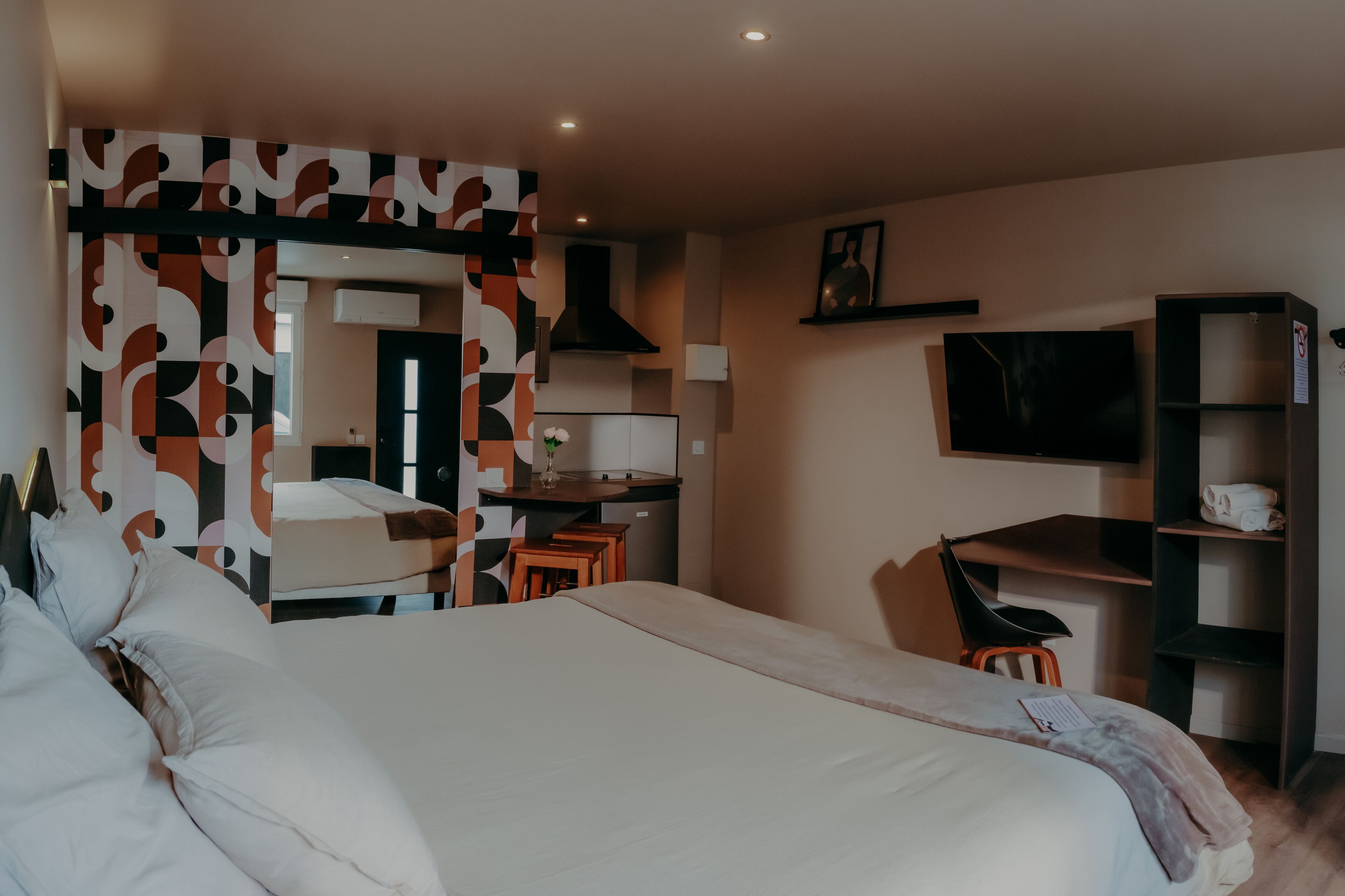 Une chambre d’hôtel avec un grand lit, un bureau avec une chaise, une télévision et une armoire.