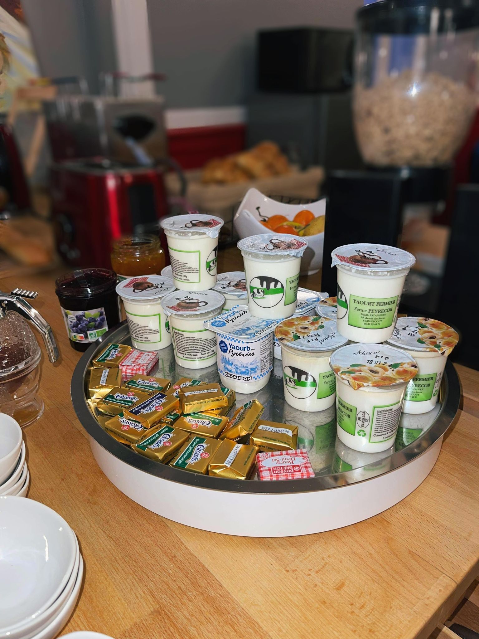 Une table sur laquelle on trouve divers aliments, notamment des pots de confitures, des pots de yaourt et des barres de chocolat.