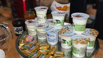 Une table sur laquelle on trouve divers aliments, notamment des pots de confitures, des pots de yaourt et des barres de chocolat.