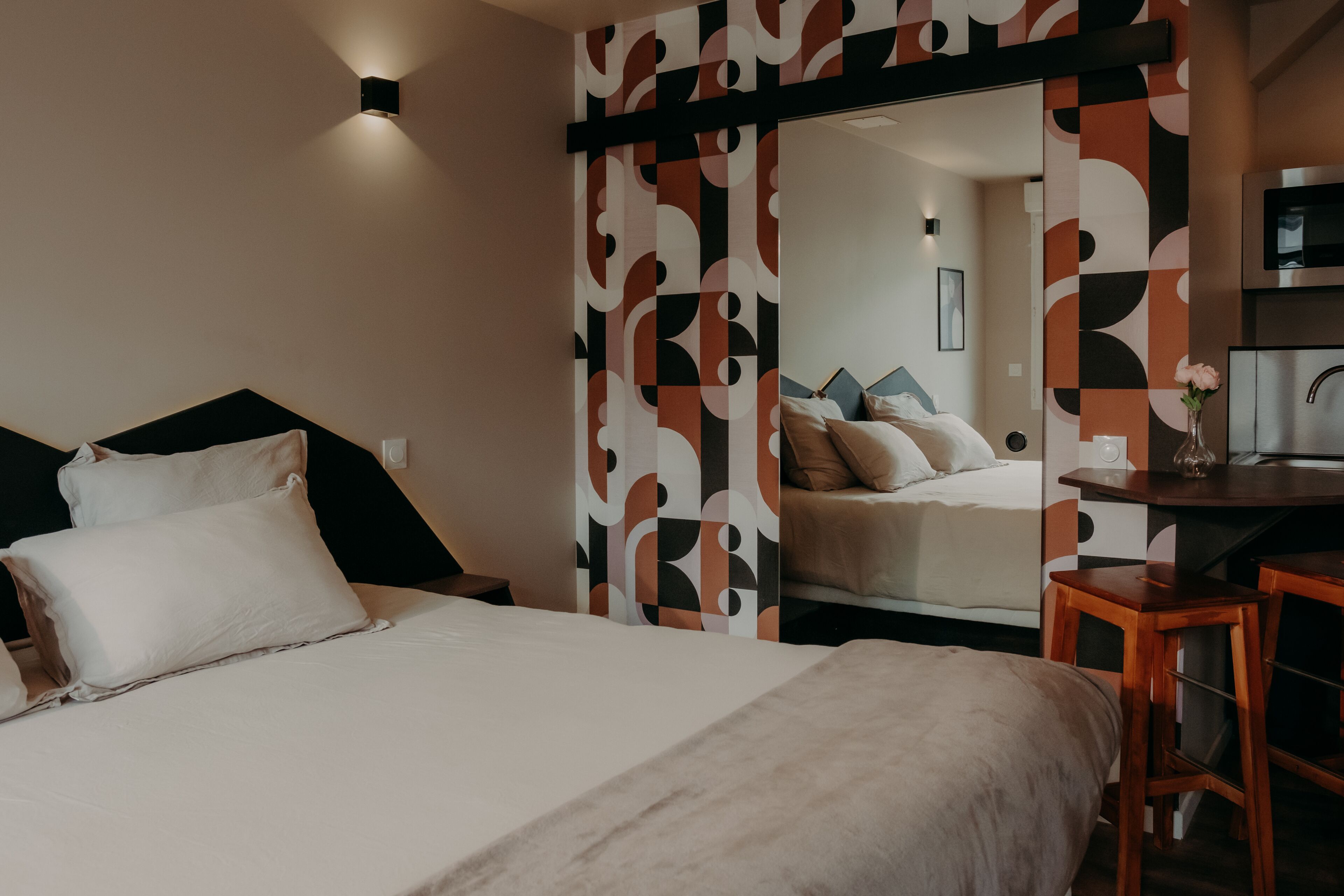 Una habitación de hotel moderna con una cama grande, un escritorio y un espejo.