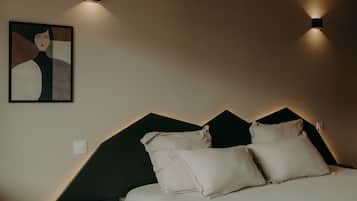 A bedroom with a bed, bedside tables, a wall-mounted light, and a piece of wall art.