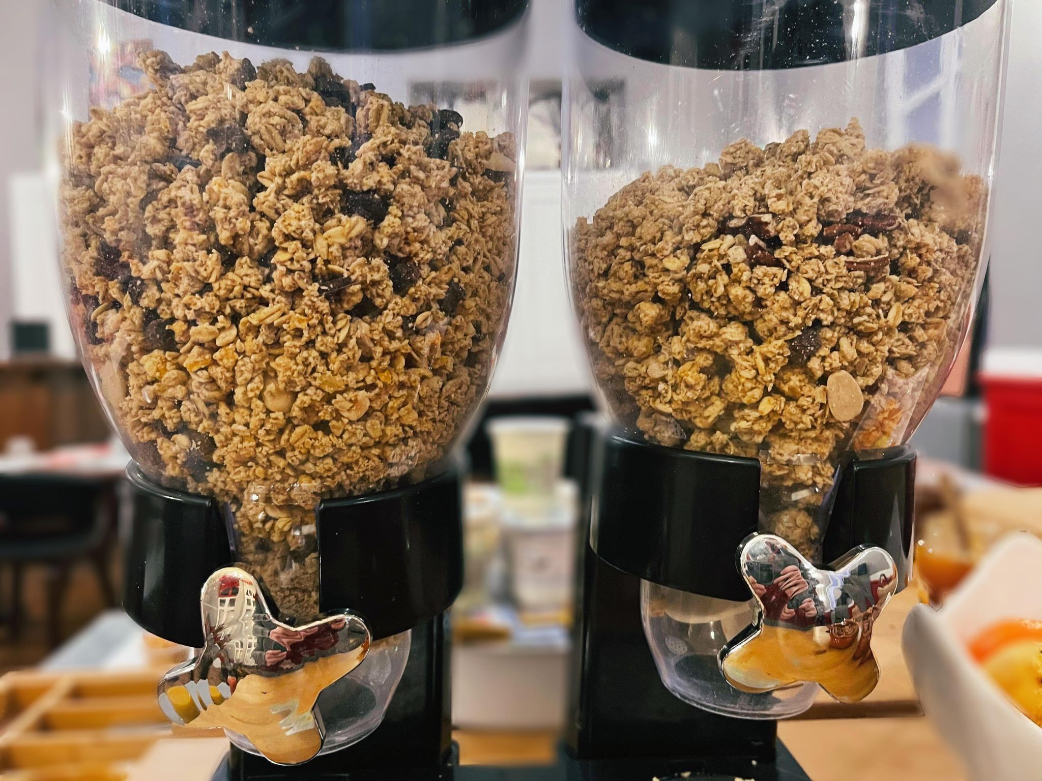 Dos recipientes de vidrio transparentes llenos de granola, cada uno con una figura metálica distinta en el fondo.
