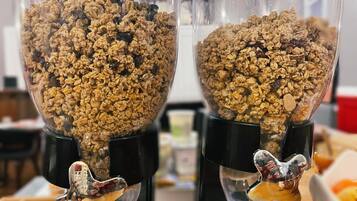 Dos recipientes de vidrio transparentes llenos de granola, cada uno con una figura metálica distinta en el fondo.